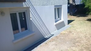 A building with two windows, a white exterior, and a gravel driveway.