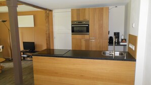 A modern kitchen with wooden cabinets, a black countertop, and stainless steel appliances. - Holiday home / B & B 't Zwaluwnest - peace, space and privacy with its own sauna (Luttenberg)