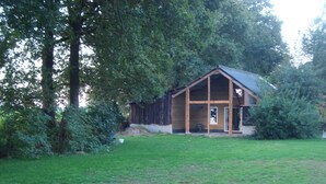 A wooden cabin with a porch, surrounded by trees and a grassy yard. - Holiday home / B & B 't Zwaluwnest - peace, space and privacy with its own sauna (Luttenberg)