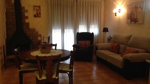 Una sala de estar con chimenea, una mesa de comedor con sillas, un sofá y una lámpara.