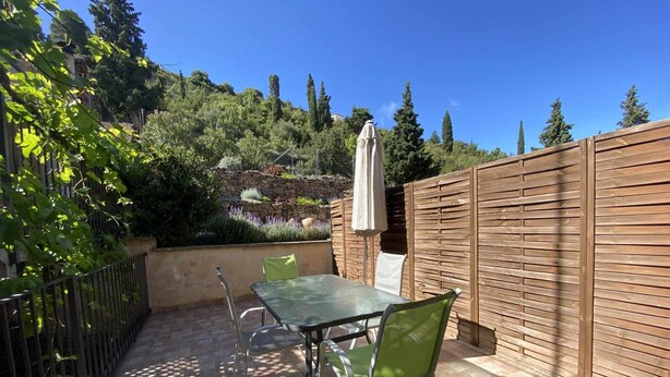 Un patio con una mesa y sillas, rodeado por una valla de madera y un muro de piedra.