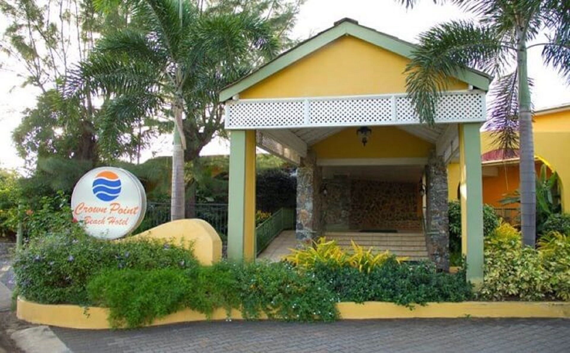 A small, yellow building with a covered entrance and a sign indicating it is a Crown Point Beach Hotel.