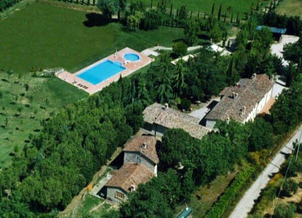 Vue aérienne d’une propriété comprenant une piscine, plusieurs bâtiments et une végétation luxuriante.