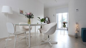 A modern dining area with a glass table, white chairs, and a vase with flowers.
