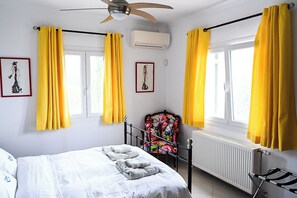 Un dormitorio con cama, una silla, un radiador y cortinas.