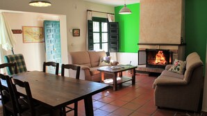 Una sala de estar con chimenea, una mesa de comedor con sillas, un sofá y una pared de acento verde.