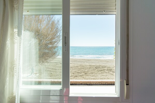 A window with a view of a beach and ocean.
