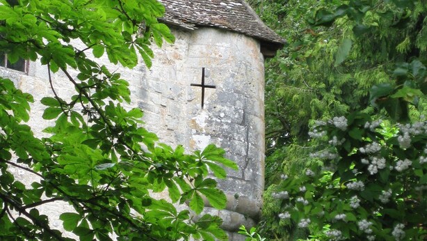 A stone building with a cross on its wall, surrounded by lush greenery. - Newly renovated village home with views over the vines of Pommard (Pommard)