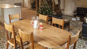 A dining area with a wooden table and chairs, a hanging light fixture, a Christmas tree, and a stone fireplace. - Newly renovated village home with views over the vines of Pommard (Pommard)