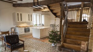A spacious living area with a large wooden staircase, a dining table, and a cozy seating arrangement. - Newly renovated village home with views over the vines of Pommard (Pommard)