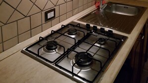 Una cocina con estufa a gas, un lavamanos y salpicadero de azulejos.