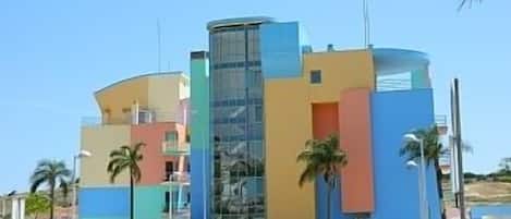 A modern building with a curved facade, large glass windows, and a mix of pastel colors.