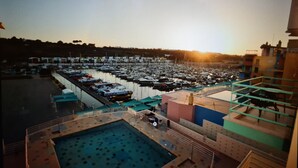A marina with boats docked, a swimming pool, and a building with a green roof.