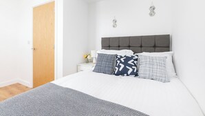 Ein Schlafzimmer mit einem Bett, einem Nachttisch, einer Holztür und zwei Wandleuchten.