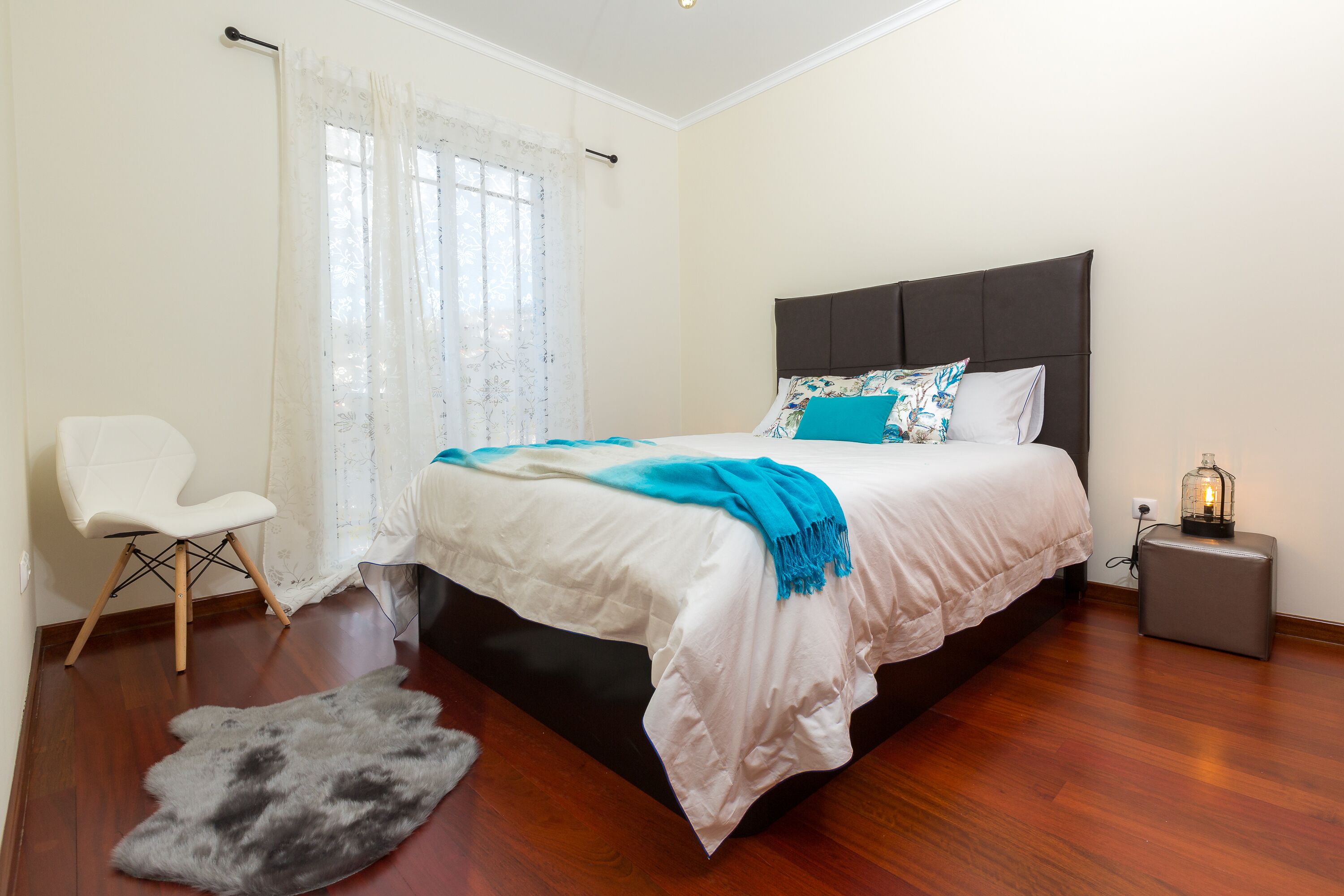 Une chambre à coucher avec un lit, une chaise, un tapis et une table de chevet avec une lampe.