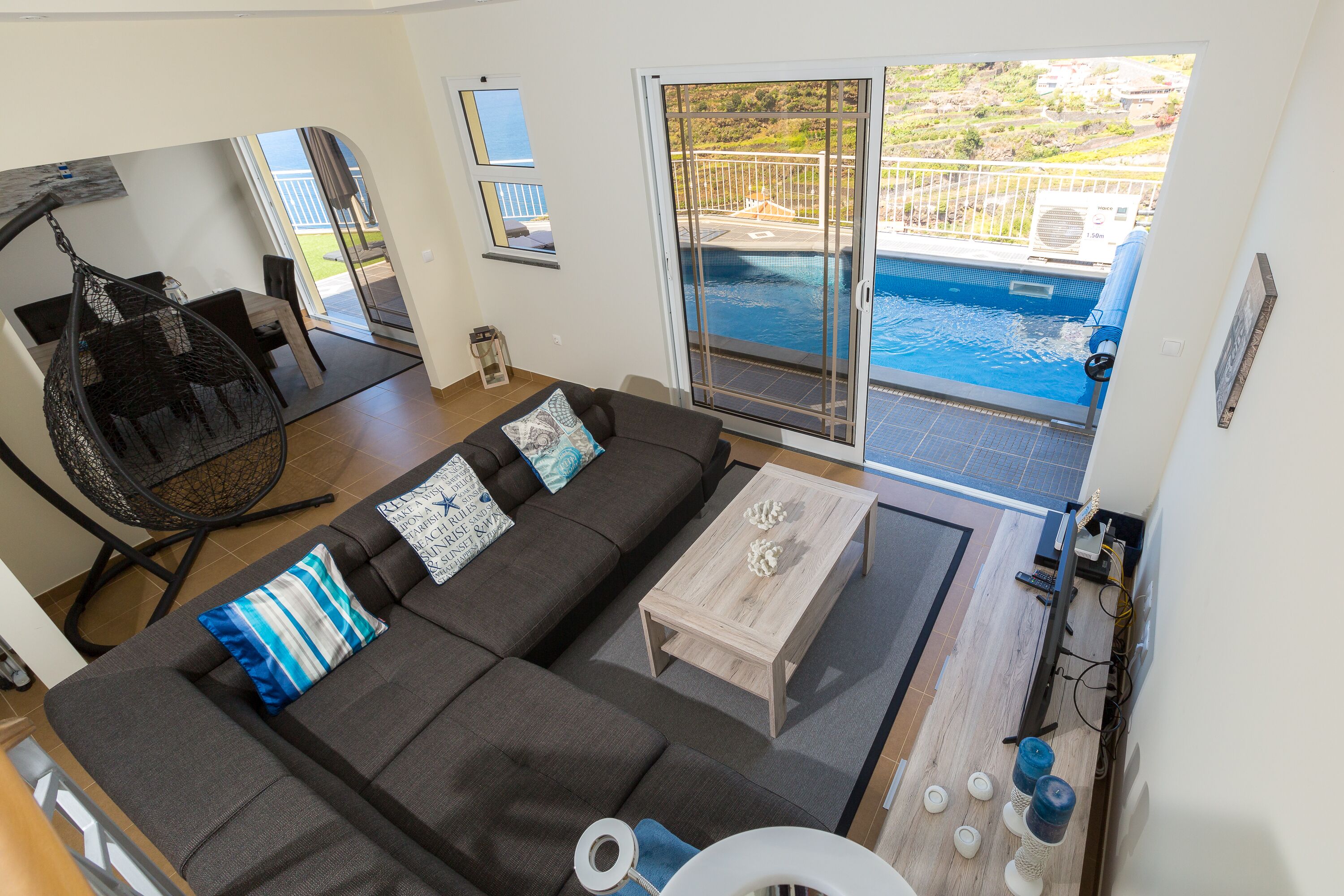 A modern living room with a sofa, coffee table, and a view of a swimming pool.