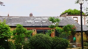 A brick building with a sloped roof, multiple windows, and a garden area with various plants and a pathway. - Family friendly in London (London)