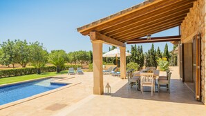 A covered outdoor area with a pool, lounge chairs, and a table with chairs. - Finca Ses Quaranta (Campos)