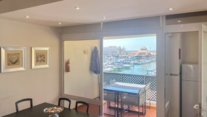 Un balcón con vista a un puerto deportivo, una mesa de comedor con sillas y dos cuadros en la pared.