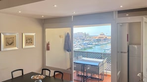 Un balcon donnant sur une marina, une table à manger avec des chaises et deux tableaux encadrés accrochés au mur.