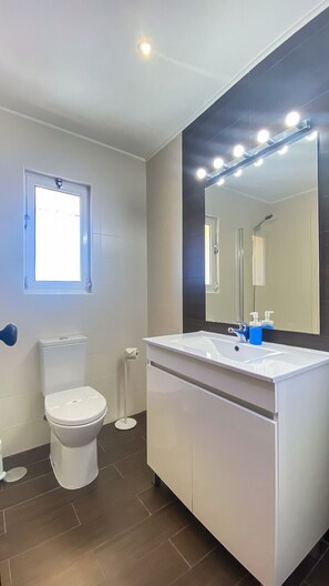 Ein Badezimmer mit Toilette, Waschbecken mit Spiegel und Fenster.