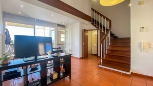 Una sala de estar con televisor, una mesa de comedor y una escalera.