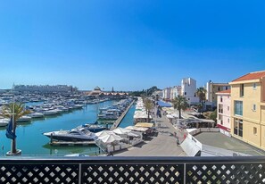 Un puerto deportivo con barcos amarrados, cielo despejado y edificios a lo largo de la costa.