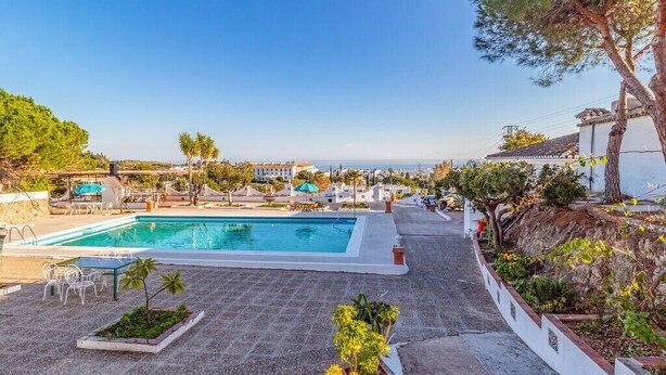 A pool area with a clear view of the sea, surrounded by greenery and a white building. - Rural house in Sierra de Mijas, private pool, ideal for families and groups. (Mijas)