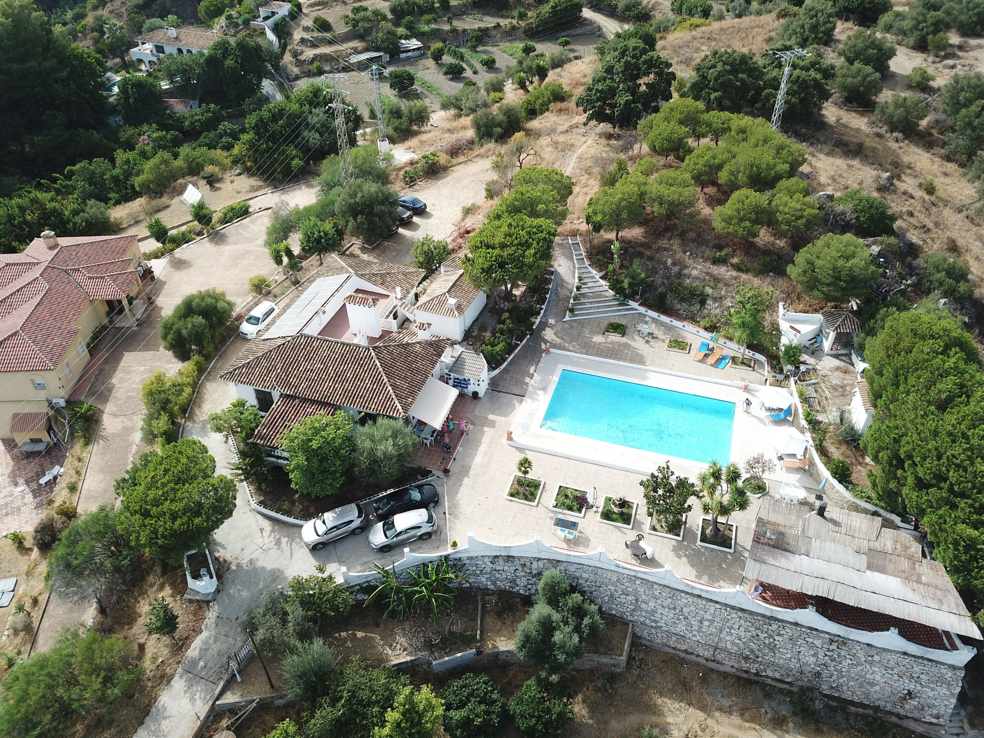 Vista aérea de um bairro residencial com piscina, várias casas e uma ponte de pedra.