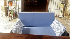 A wooden bench with a blue cushion in a rustic outdoor area with a stone wall and an arched doorway leading to a dining area. - Rural house in Sierra de Mijas, private pool, ideal for families and groups. (Mijas)