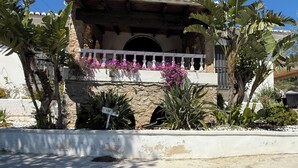 A stone archway leading to a balcony with white railings and pink flowers. - Rural house in Sierra de Mijas, private pool, ideal for families and groups. (Mijas)