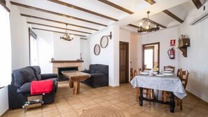 A living room with a fireplace, a dining table set for four, and a sofa with a red throw.