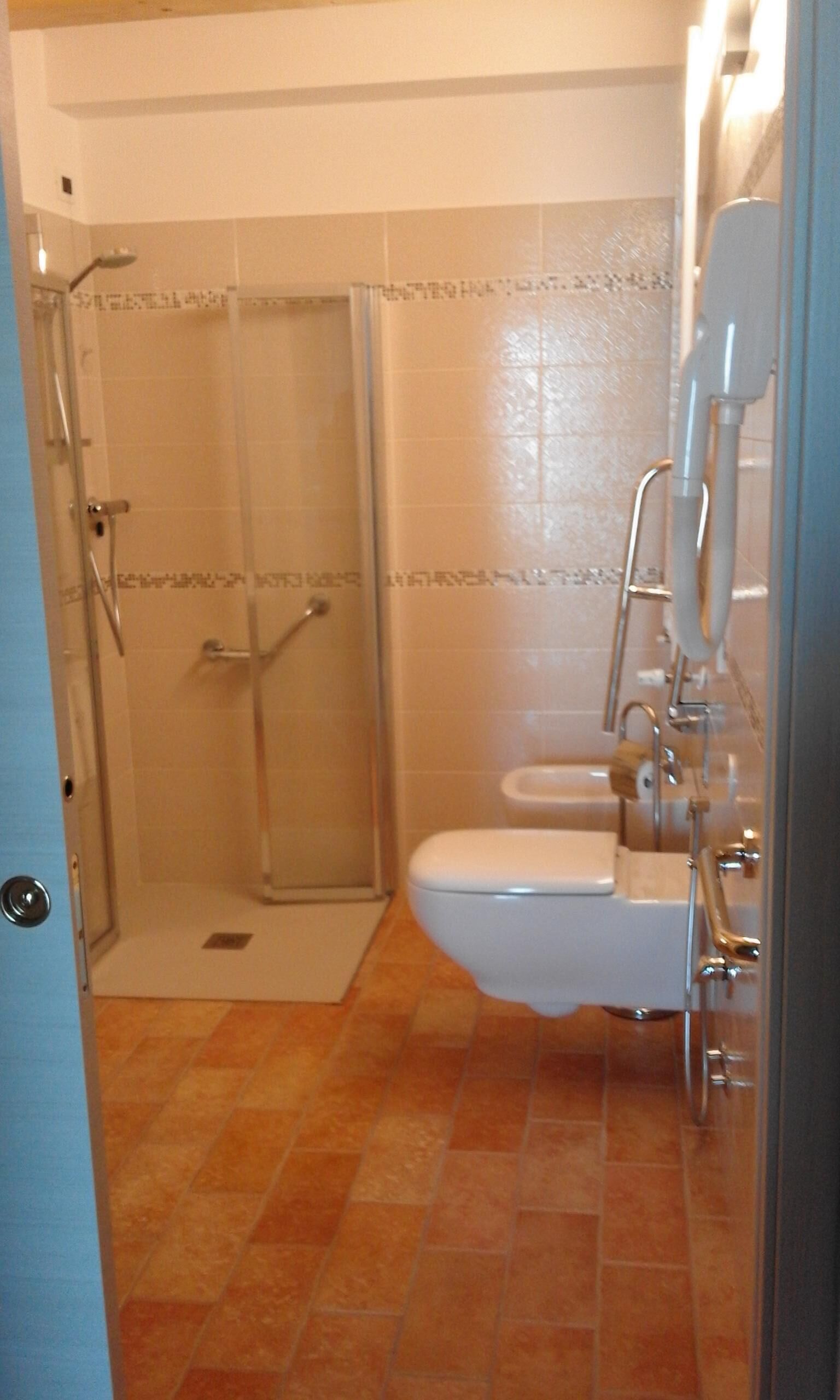 A bathroom with a glass-enclosed shower, a toilet, and a sink.