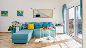 Uma sala de estar moderna com um sofá azul-turquesa, uma mesa de centro e uma janela grande com cortinas.