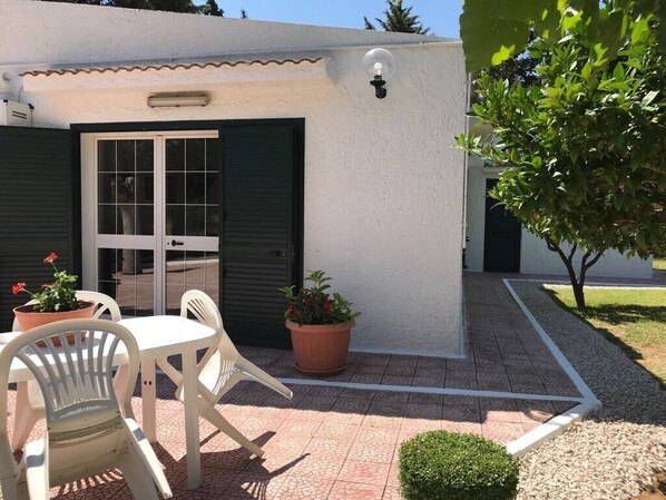 A small building with a white exterior, a door with glass panels, and a small patio area with a table and chairs. - VILLA IL CARRUBO-unit2 € 500 per week with 3 bedrooms for 10 persons (Pisticci)