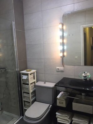 A bathroom with a glass shower enclosure, a toilet, a sink with a mirror, and a towel rack. - Cozy apartment near the beach (Carboneras)