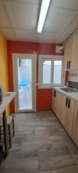 A kitchen with a red wall, a white door, and a window.