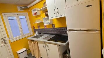 Una cocina compacta con armarios blancos, un lavamanos y un refrigerador.