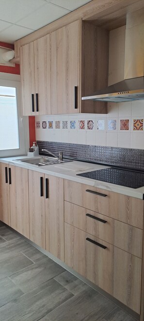 Een moderne keuken met houten kastjes, een betegelde spatwand en een roestvrijstalen spoelbak.