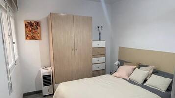 Un dormitorio con cama, armario, mesita de noche y lámpara de techo.