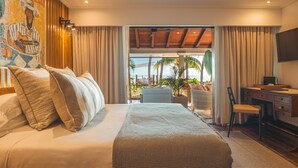 A hotel room with a bed, a desk, a chair, and a view of the outdoors. - Villa Matahari by muse villas (Rivière Noire)