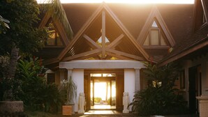 A building with a triangular roof structure, a central entrance, and a garden with tropical plants. - Villa Matahari by muse villas (Rivière Noire)