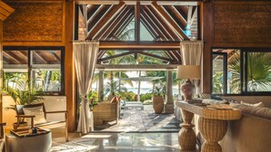 A spacious lobby with a high ceiling, large windows, and a view of palm trees. - Villa Matahari by muse villas (Rivière Noire)