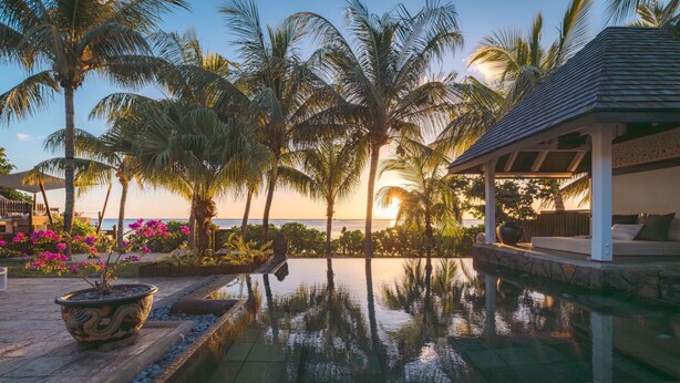 A pool with palm trees and a sunset view. - Villa Matahari by muse villas (Rivière Noire)