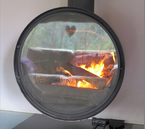 A circular wood-burning stove with visible flames.