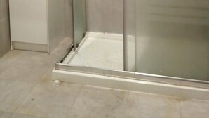 Et bruseområde med glasvægge og et hvidt skab til venstre.