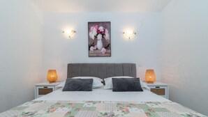A bedroom with a bed, two bedside lamps, a floral painting on the wall, and a quilt on the bed. - SABLIC 3 apartment with sea view, 30m from a beach in OKRUG GORNJI (Okrug Gornji)