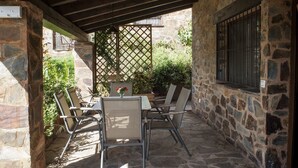Une terrasse extérieure avec des murs en pierre, une table en bois et des chaises en métal.