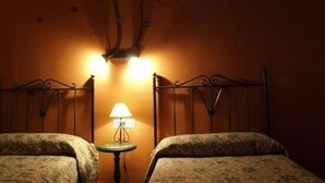 Une chambre avec deux lits, une petite table avec une lampe et un luminaire fixé au mur.