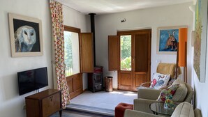 Un salon chaleureux avec un téléviseur, des meubles en bois, une cheminée et des œuvres d’art accrochées aux murs.